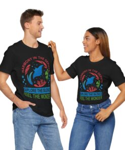 A couple wearing matching black diving t-shirts featuring the 'Harmony in the Depths' design, showcasing a dolphin, coral, and ocean-themed elements. Perfect for scuba divers and ocean lovers