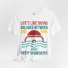 White diving t-shirt with a split-view design of a diver’s mask, featuring the phrase 'Life's Like Diving – Balance Between Surface Views and Deep Wonders' in bold typography with ocean-inspired colors