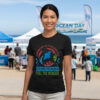 Woman standing outdoors at a beach event wearing a black premium marine life graphic tee with a custom colorful manta ray illustration