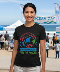 Woman standing outdoors at a beach event wearing a black premium marine life graphic tee with a custom colorful manta ray illustration