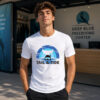 A young man wearing the white "Tail & Tide" freediving graphic tee