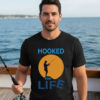 Man standing on a boat deck wearing a black premium fisherman tee with an orange sunset graphic print