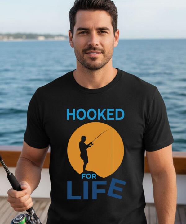 Man standing on a boat deck wearing a black premium fisherman tee with an orange sunset graphic print