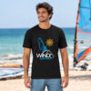 Man wearing the black Seasportees windsurfing t-shirt standing on a sunny beach with windsurfing gear in the background.
